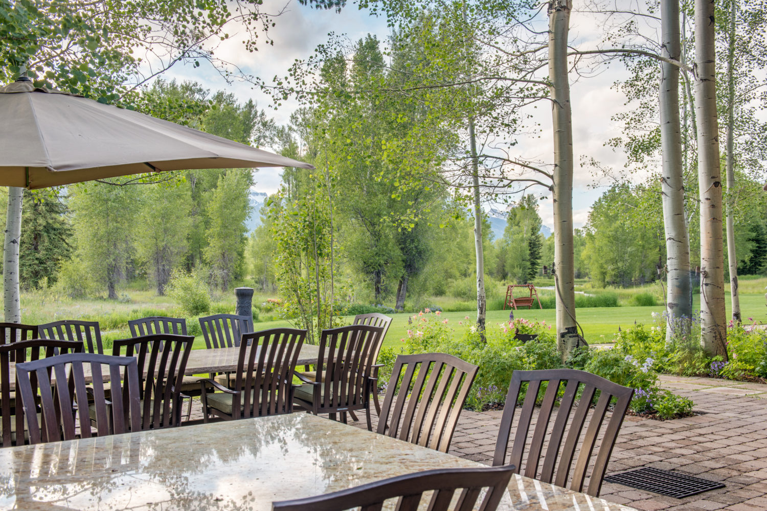 main_house_outdoor_dining A large outdoor dining set up in front of a lawn and mountains